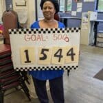 Woman holding sign that says Goal: 5000 and the number 1544