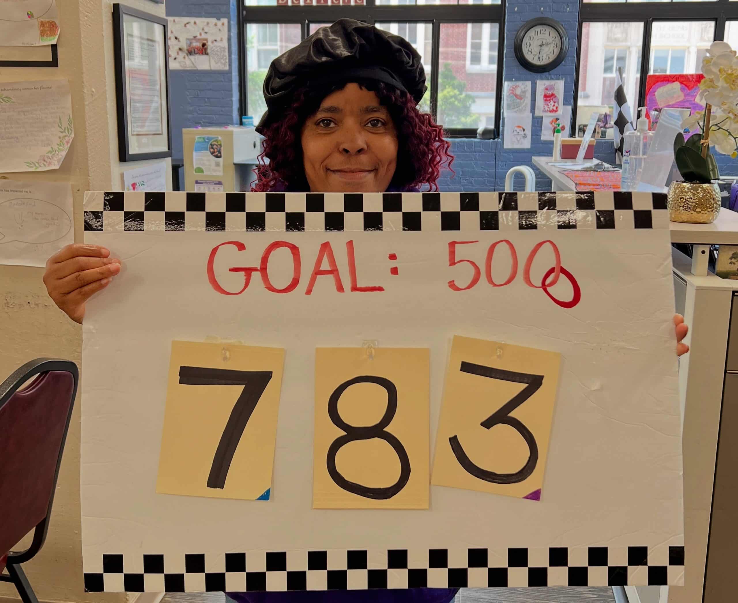 Woman holding sign that says Goal: 5000 and the number 783